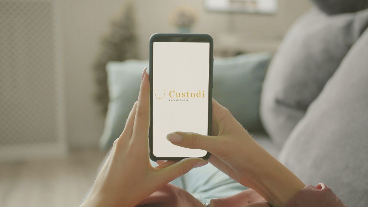 Madre revisando app de coparentalidad en su teléfono